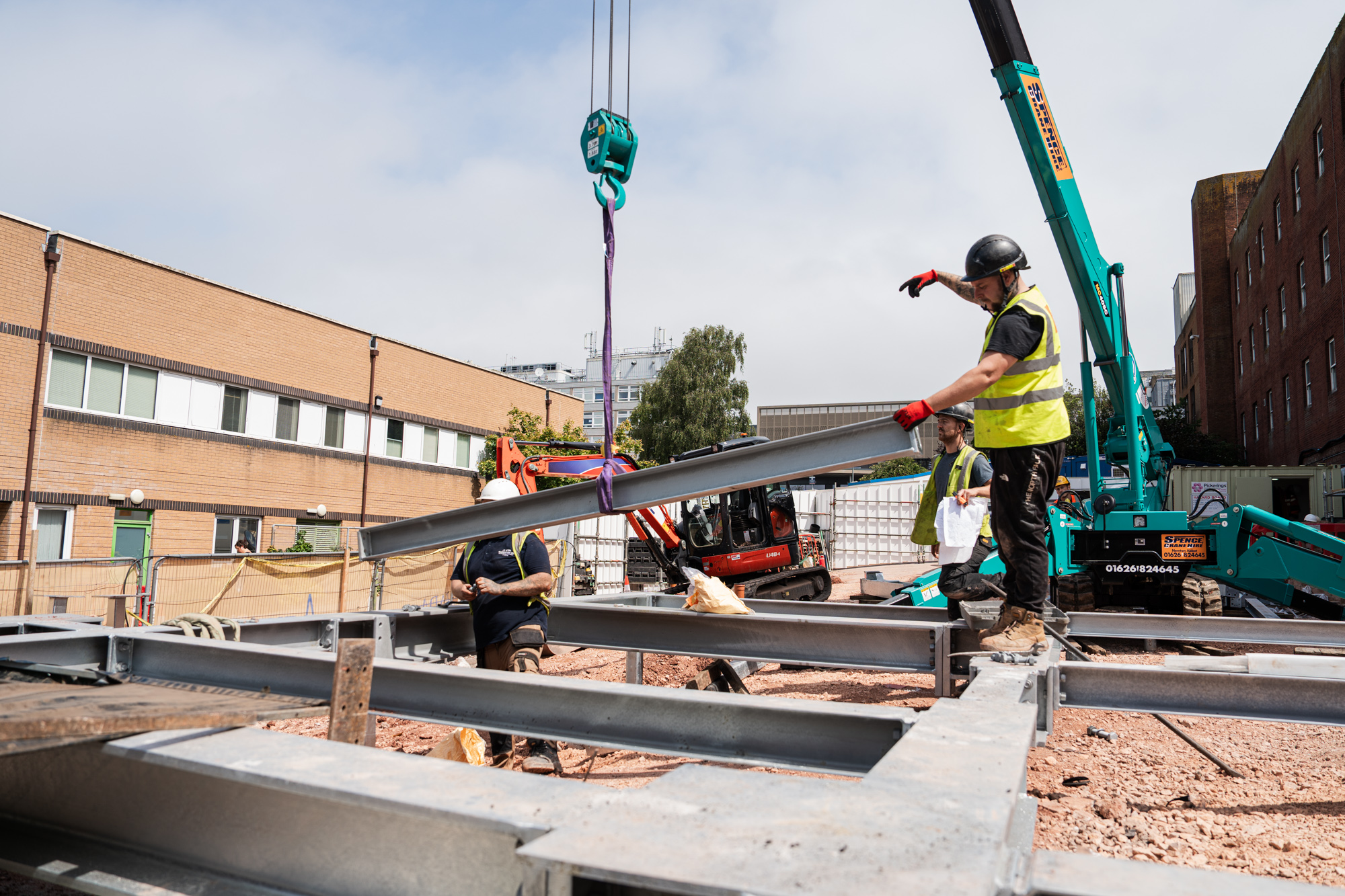 a site worker holding a steel beam being lifted